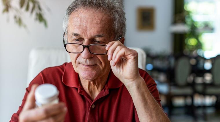 Mand ser på en beholder med medicin